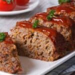 Meatloaf with ketchup closeup sliced on a white plate, vertical