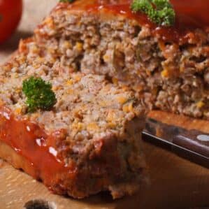 meat loaf with ketchup and vegetables close-up on chopping board. horizontal