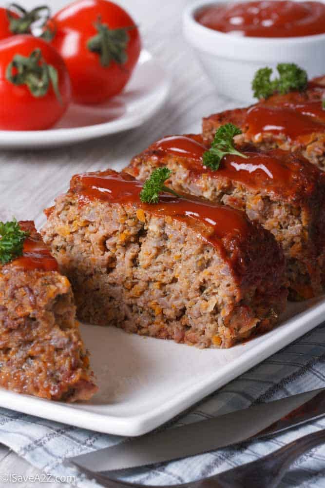 Meatloaf with ketchup closeup sliced on a white plate, vertical