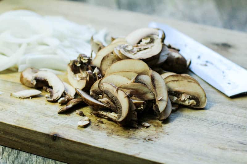 mushrooms and onions sliced on a cutting board