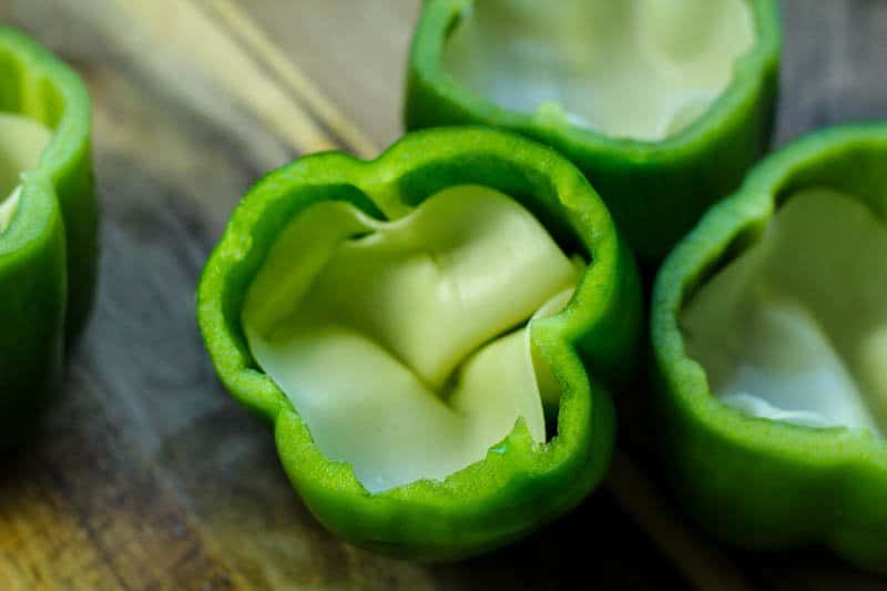 green peppers stuffed with provolone cheese on a cutting board