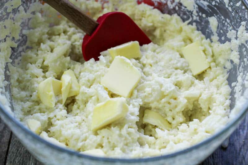 Mashed cauliflower with butter in a glass bowl.