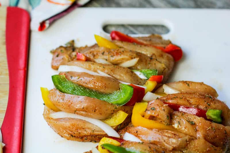 Raw hasselback chicken with onions and peppers