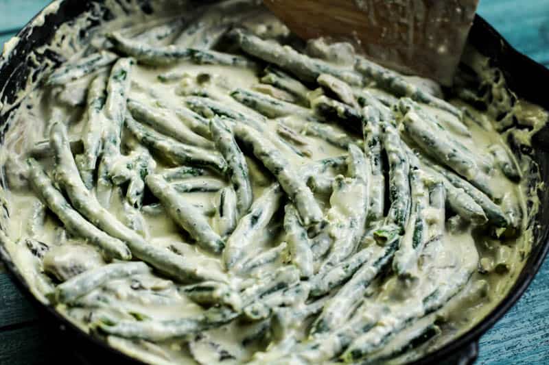 Green beans smothered in a creamy sauce in a pan.