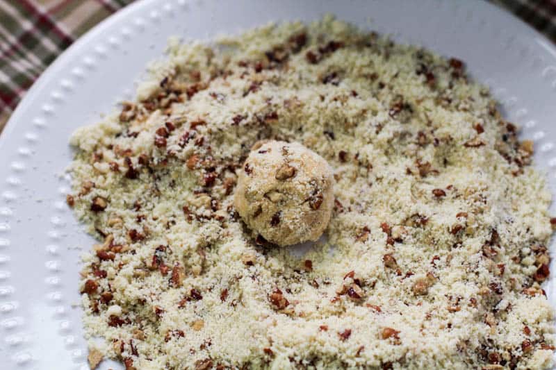 A ball of pumpkin cream cheese mixture in crushed pecans and almond flour