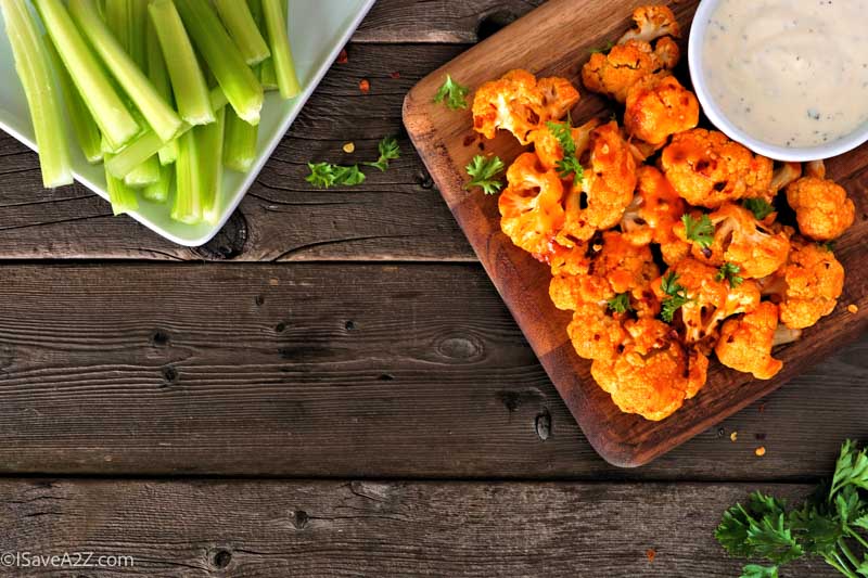 Cauliflower buffalo wings. Top view table scene against a wood background with copy space. Healthy eating, plant based meat substitute concept.