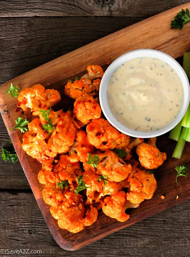 Cauliflower buffalo wings with celery and ranch dip. Top view with a dark slate background. Healthy eating, plant based meat substitute concept.