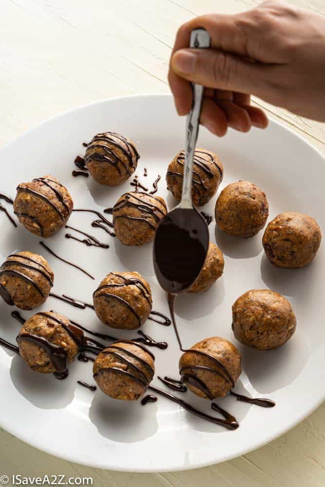 pecan pie truffles rolled into balls on a white plate with chocolate being drizzled over the top with a spoon